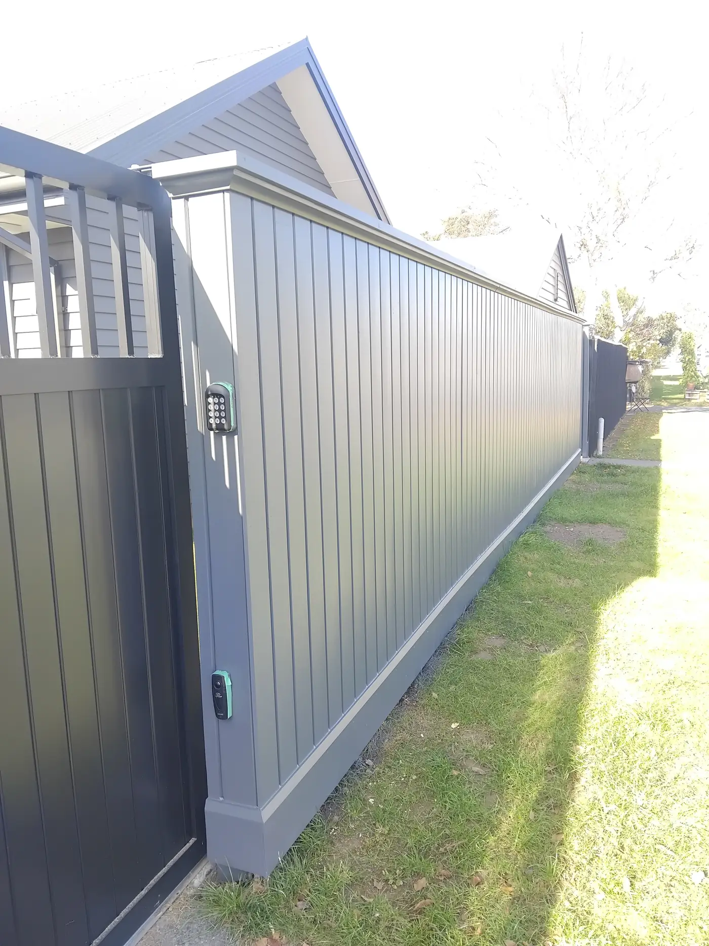 Grey steel privacy fence with a keypad gate